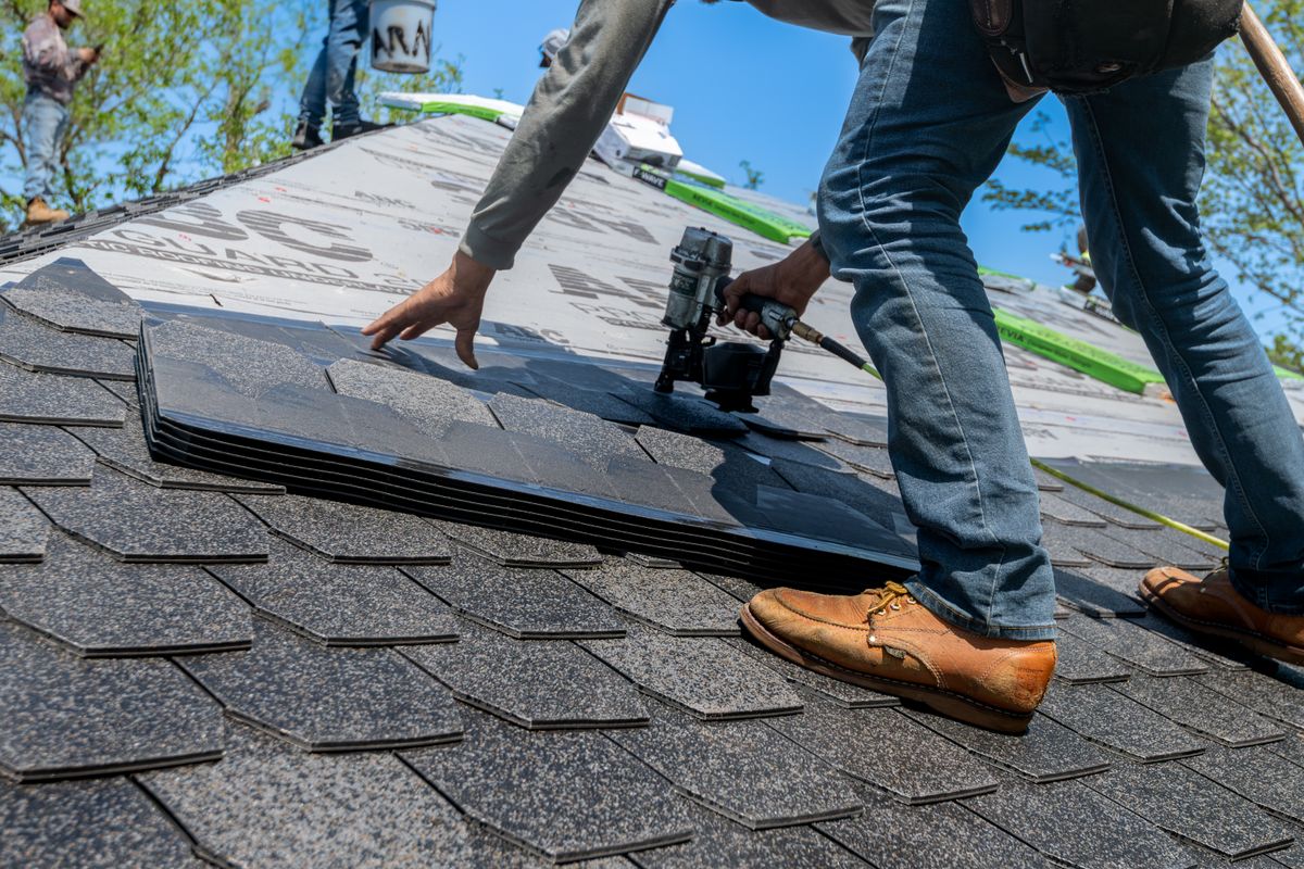 roofer installing shingles on new roof